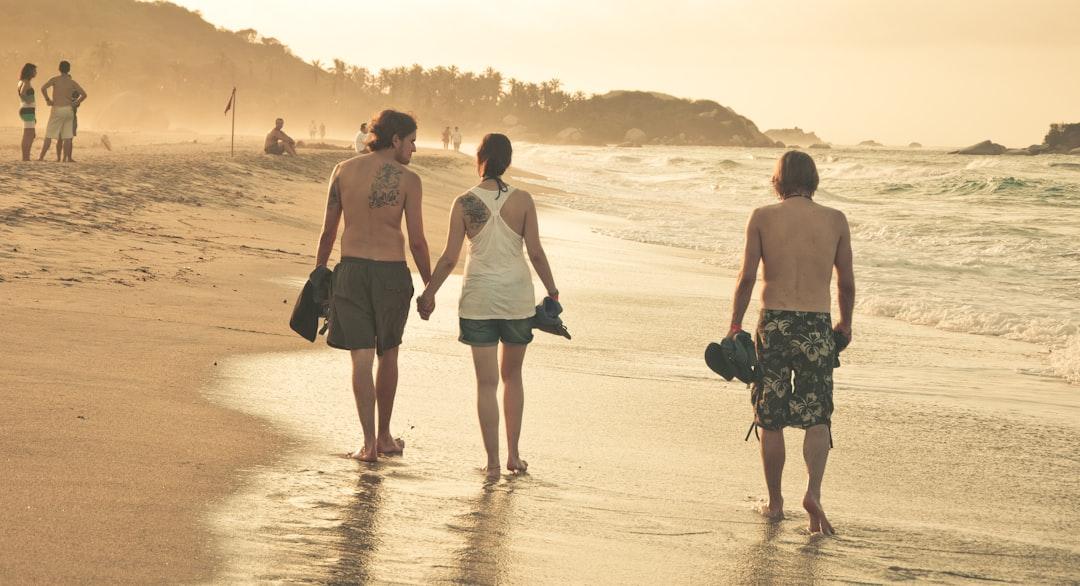 3 men and 2 women walking on beach during daytime