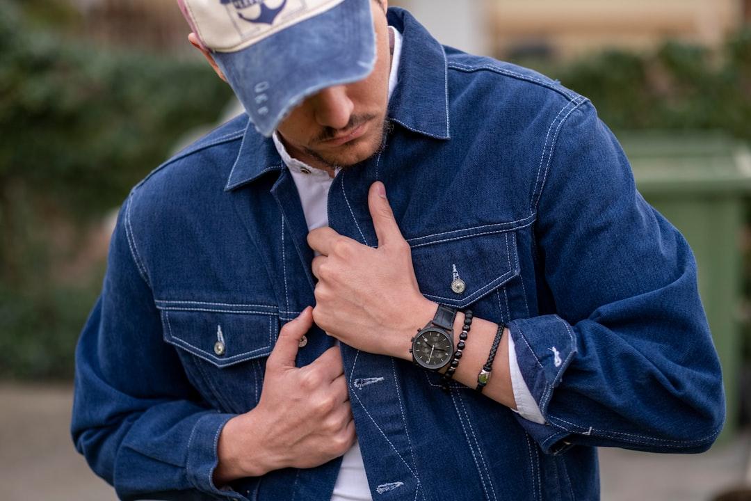 man in blue denim jacket wearing white and blue fitted cap
