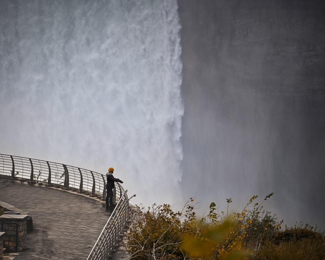 A man stands on the ledge overlooking Niagara Falls. 