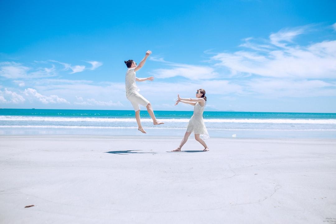 man and woman playing on white sand near seashore during daytime