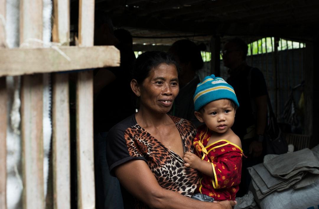 A mother and young child with happy yet desperate eyes as they receive donations at a local shelter. This photo was taken two days after Mount Agung on Bali erupted forcing the airport to close and thousands of villagers to flee into makeshift shelter centres. Bali, Indonesia 29 November 2017.