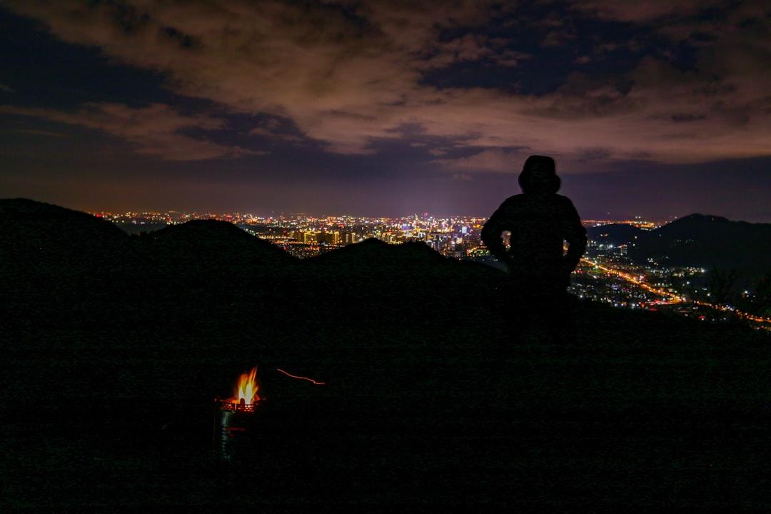 silhouette of person standing on mountain top during nighttime