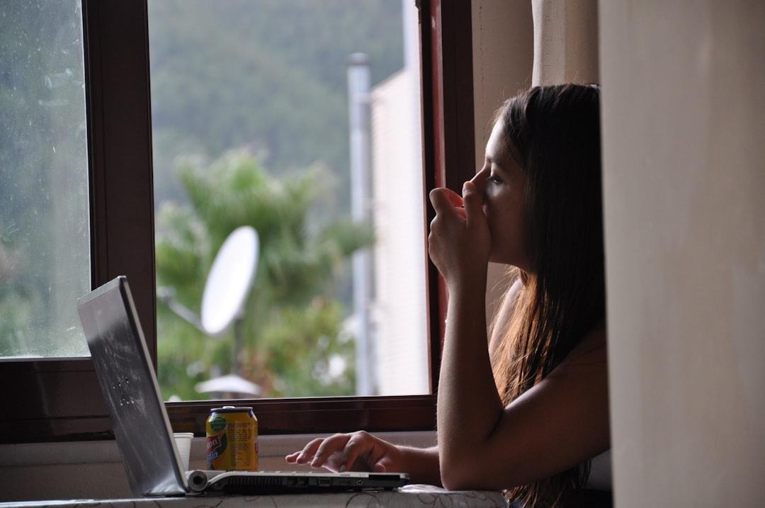 Girl Sitting by a Window with Her Laptop