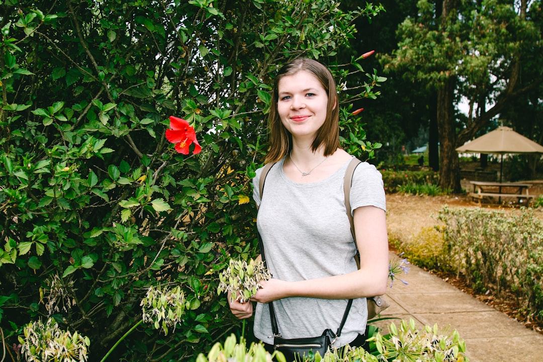 A young and beautiful Danish girl, standing next to an exotic flower in Nairobi, Kenya